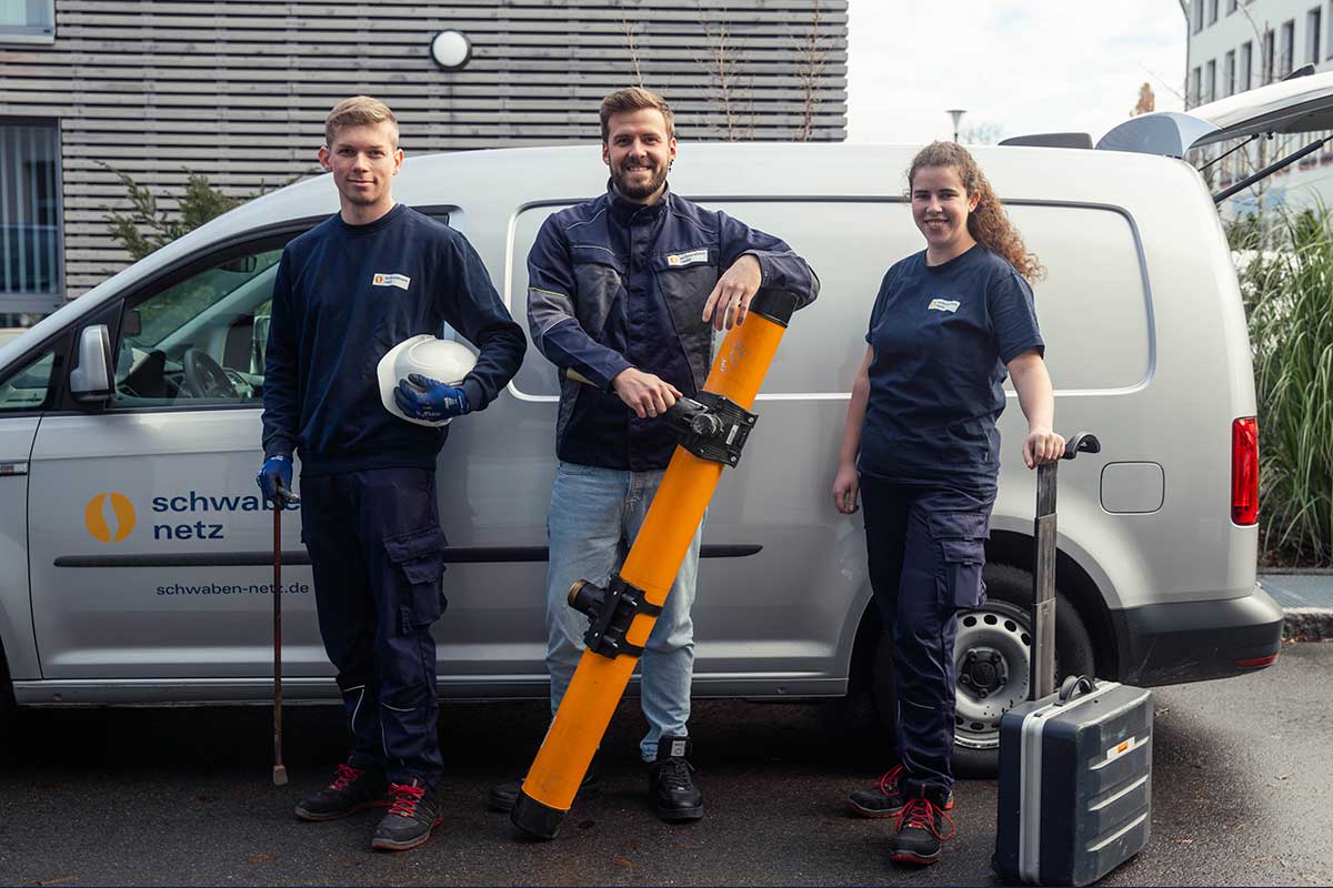 Drei Anlagenmechaniker in Ausbildung stehen vor einem Kleintransporter.