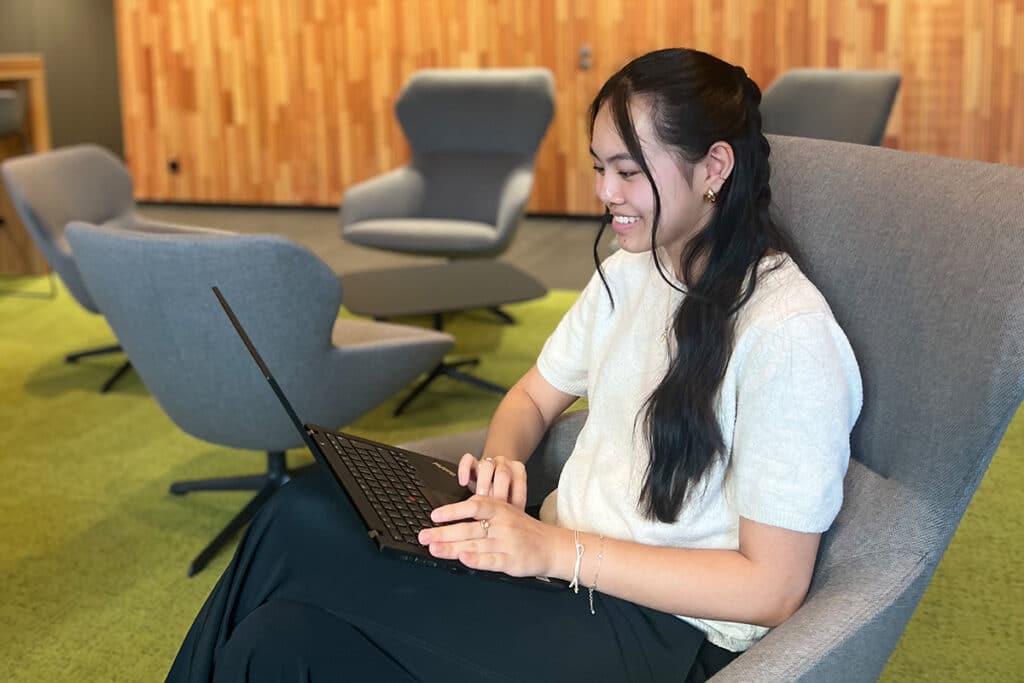 Duale Studentin sitzend im Stuhl mit Laptop.
