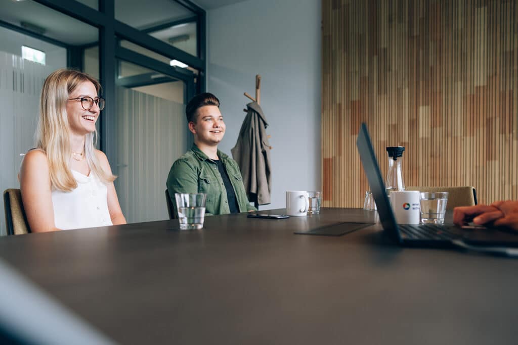 Eine junge Frau und ein junger Mann sitzen in einem Meeting.
