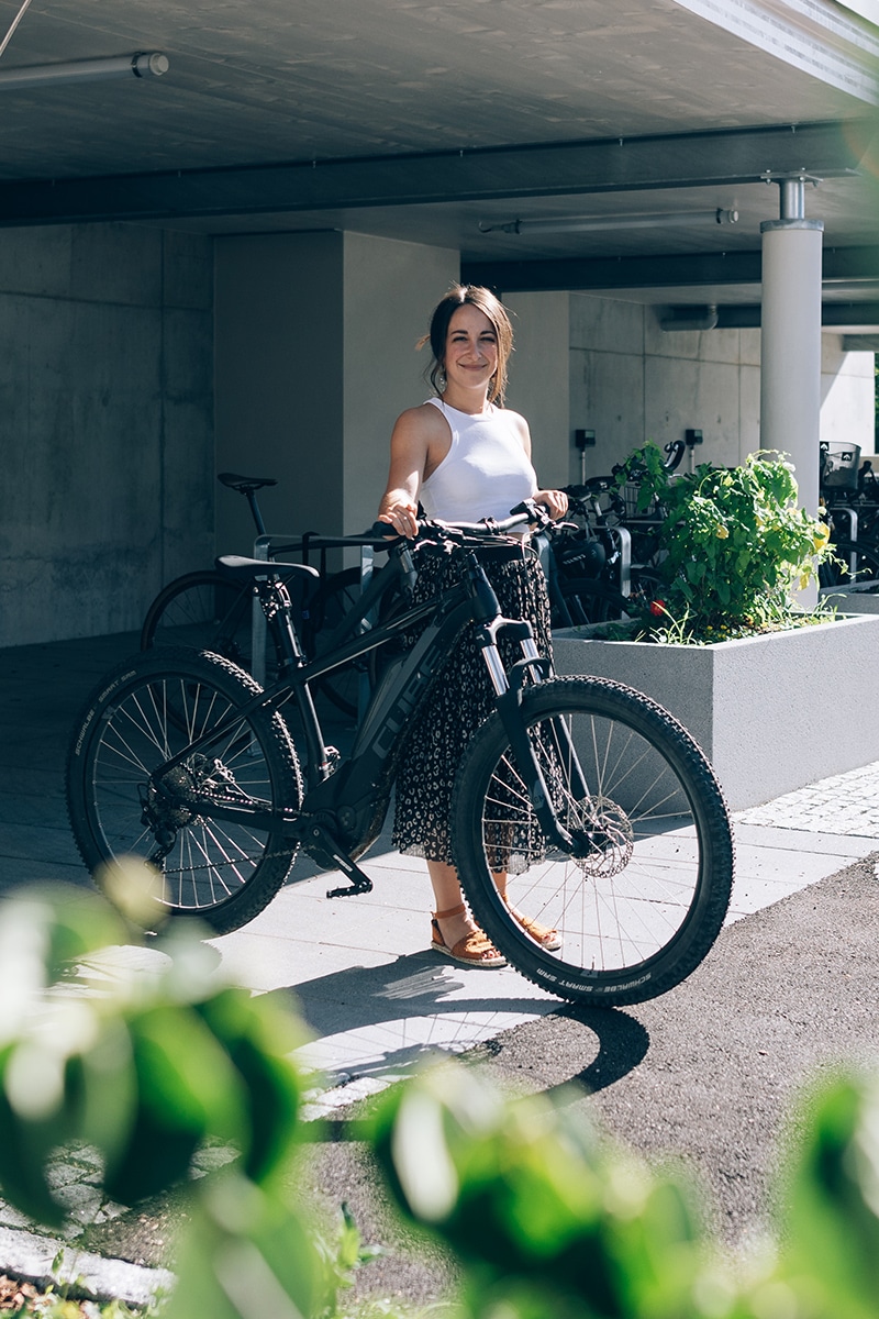 Eine junge Frau schiebt ein schwarzes E-Bike aus einer Garage.