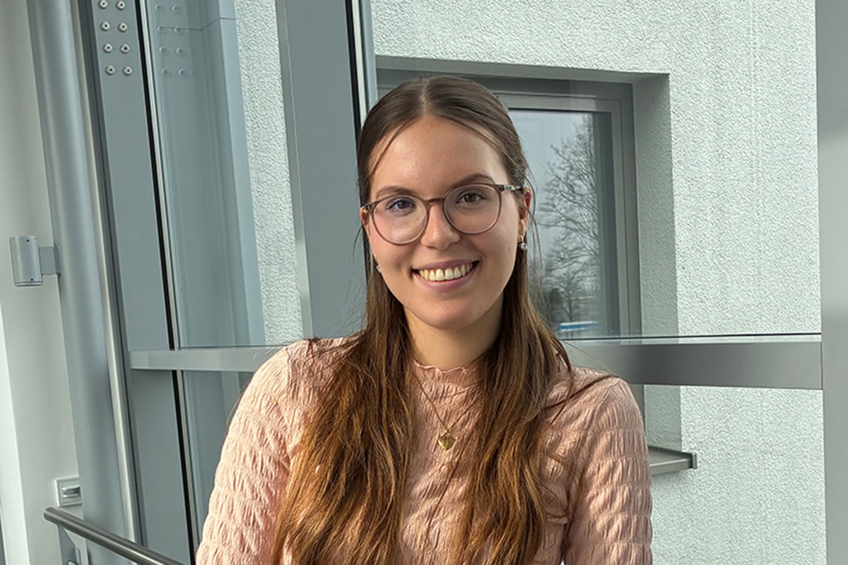 Frau lächelnd angelehnt an ein Geländer.