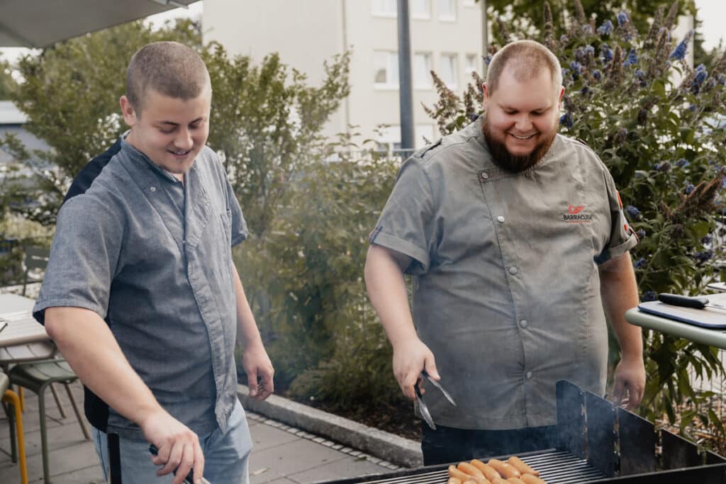 Zwei Männer stehen am Grill.